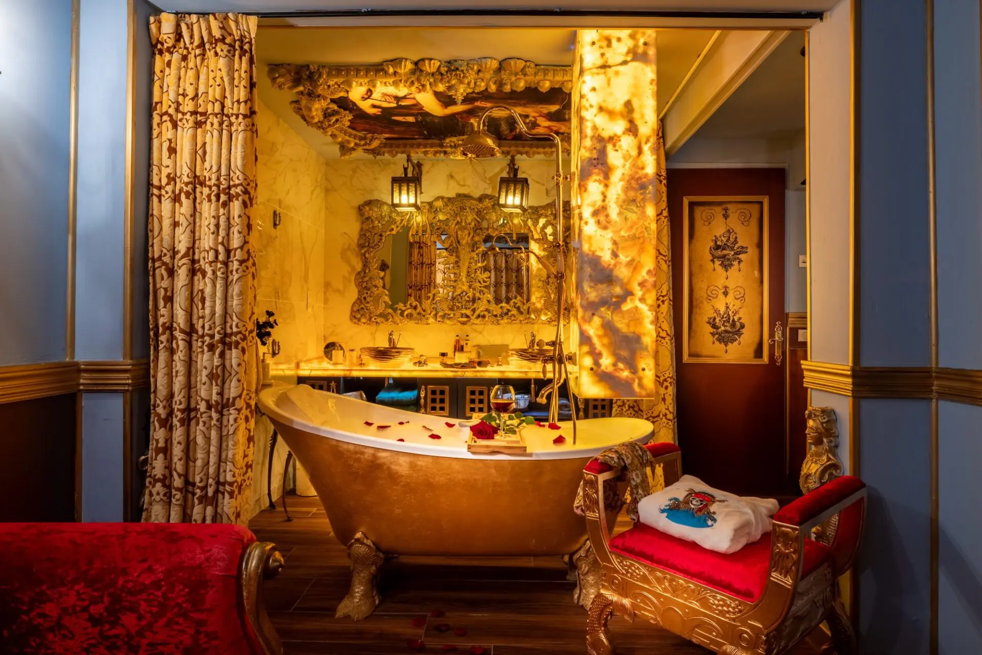 Salle de bain en or avec baignoire et pétales de roses dans le séjour d'une chambre pour 3 personnes