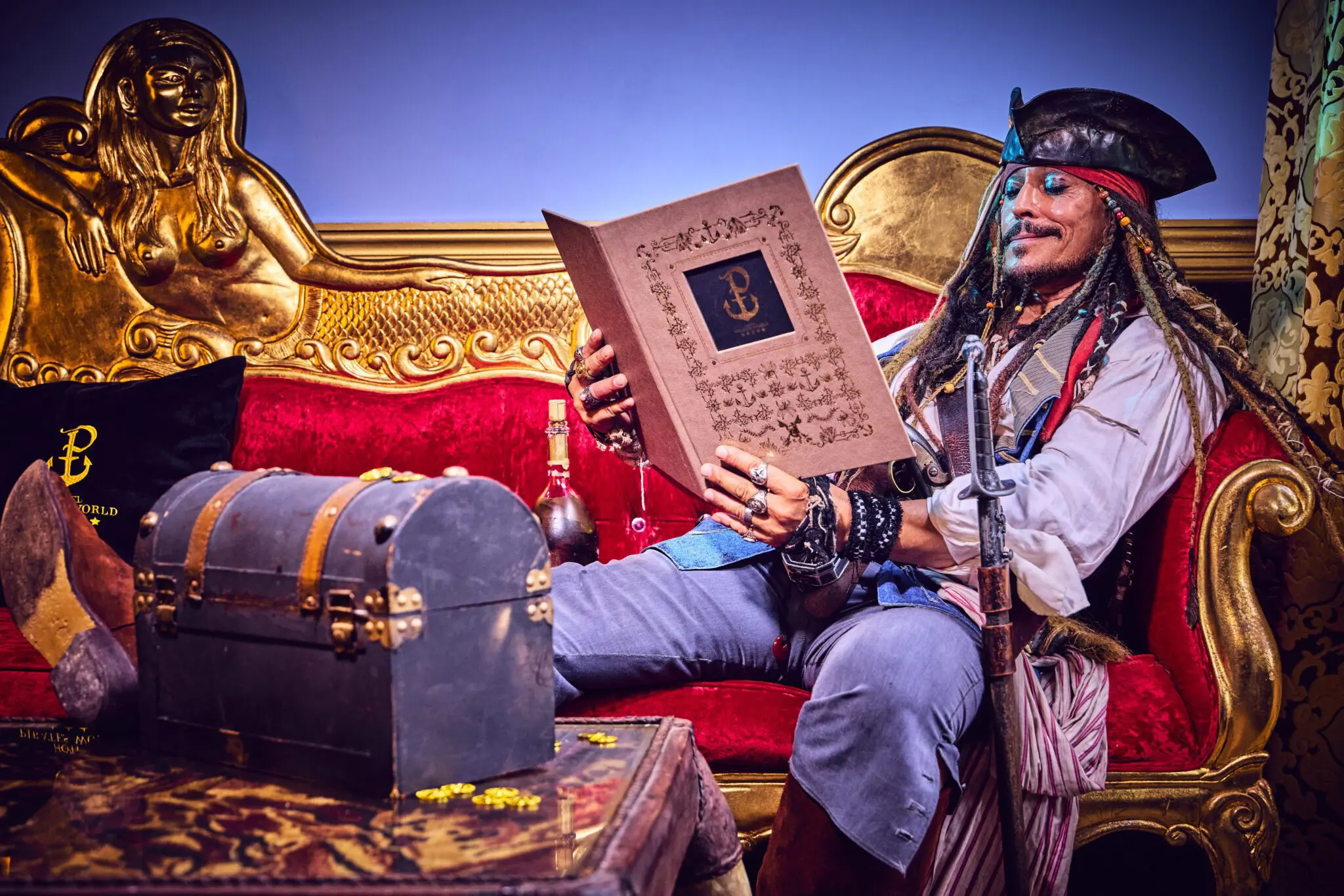 Sosie Pirate qui lit la carte du room service sur le canapé d'une chambre d'hôtel 5 étoiles